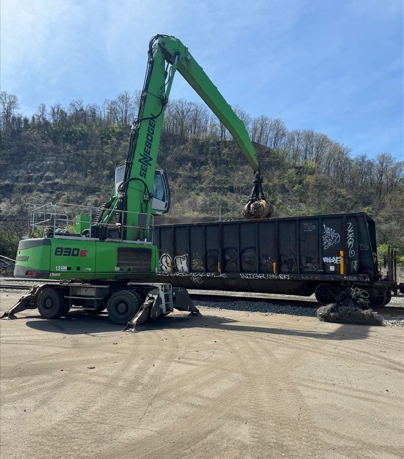 Material handler loading an open-top container truck in the terminal yard